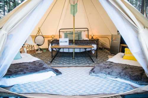 Cozy glamping tent interior with a double bed, two single beds, decorative pillows, and welcoming decor.