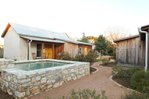 A serene outdoor scene featuring a stone pool surrounded by rustic buildings and a winding path.