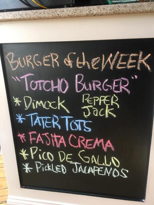 Chalkboard menu listing the "Totcho Burger" of the week with ingredients: Dimock, Pepper Jack, Tater Tots, and more.