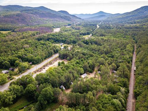 Aerial view of a lush green valley surrounded by mountains, with a winding road and scattered homes among the trees.