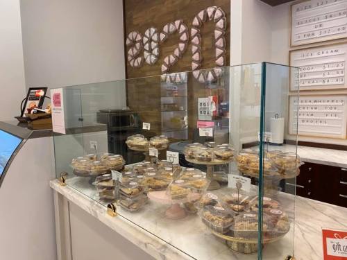 A display case filled with various desserts and pastries, with a menu board in the background.