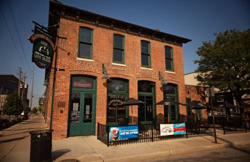 A brick building with green accents, featuring outdoor seating and signs indicating it's open for business.