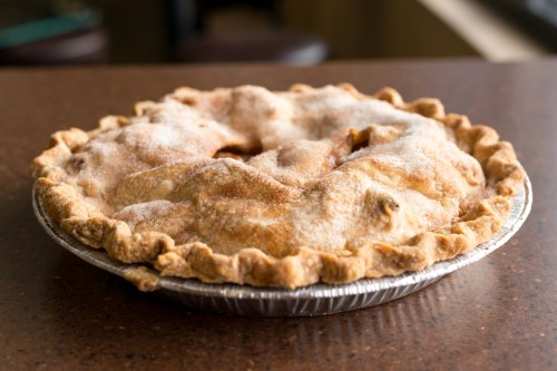 A freshly baked apple pie with a golden crust and a sprinkle of sugar on top, sitting on a countertop.
