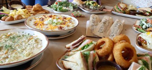A spread of various dishes including salads, sandwiches, soups, and appetizers on a table.