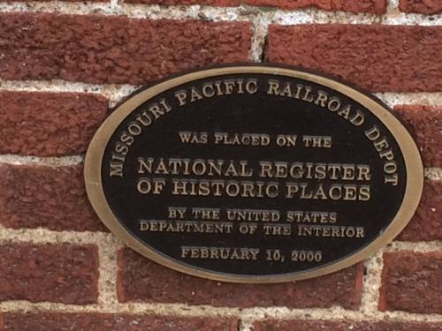 Plaque on a brick wall marking the Missouri Pacific Railroad Depot as a historic place, dated February 10, 2000.