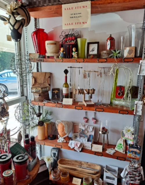 A display shelf with various decorative items, candles, jewelry, and plants, labeled "Sale Items."