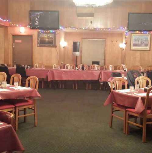 A cozy restaurant interior with tables set for dining, soft lighting, and festive decorations.