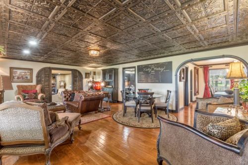 Cozy living room with ornate ceiling, elegant furniture, and a chalkboard wall, creating a warm, inviting atmosphere.