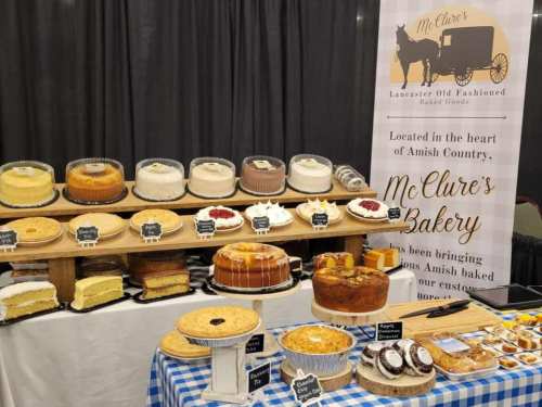 A display of various baked goods, including cakes and pies, at McClure's Bakery, with a checkered tablecloth.