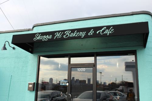 Exterior of Sluggo's Hi Bakery & Café, featuring a turquoise wall and a black sign with the café's name.