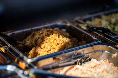 A close-up of a metal serving tray filled with golden, finely chopped food, likely a side dish.