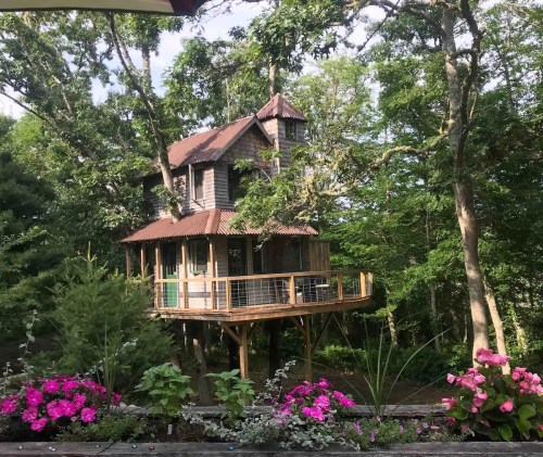 A charming treehouse surrounded by lush greenery and colorful flowers in a serene outdoor setting.
