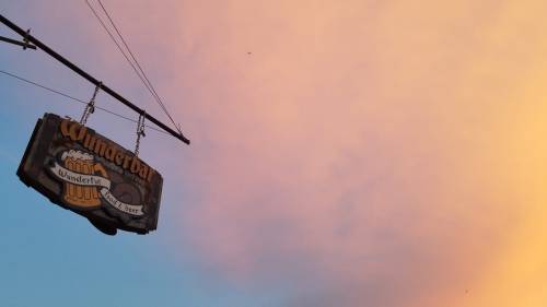 A vintage sign for "Wunderbar" hangs against a colorful sunset sky.