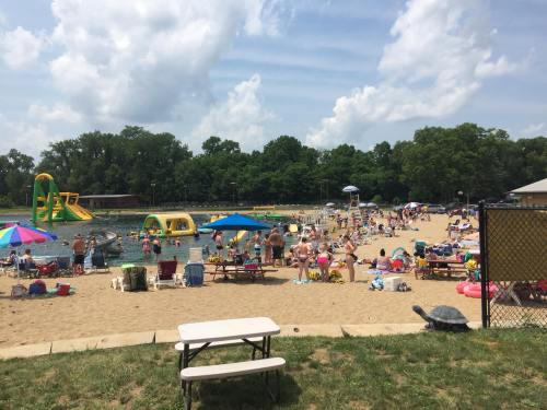 A busy beach scene with people sunbathing, swimming, and enjoying inflatable water attractions under a partly cloudy sky.
