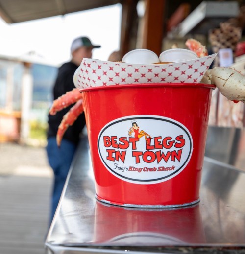 A red bucket labeled "Best Legs in Town" filled with crab legs and eggs at a seafood shack.