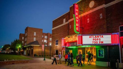 A vibrant theater marquee at dusk, with people walking in for an Atlanta Pops performance.