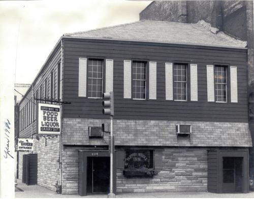 Historic building with a sign for food, beer, and liquor, featuring a stone and wood exterior. Year noted: 1984.