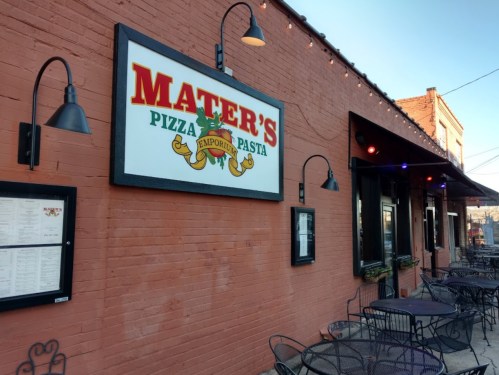 Exterior of Mater's Pizza Emporium, featuring a colorful sign and outdoor seating with tables and chairs.