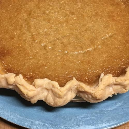 A golden-brown pie with a flaky crust, resting on a blue plate.