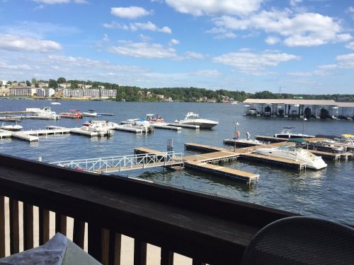 A scenic view of a marina with boats docked, under a blue sky with fluffy clouds.