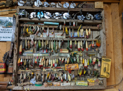 A wooden display board filled with various fishing lures and tackle, showcasing a variety of colors and styles.