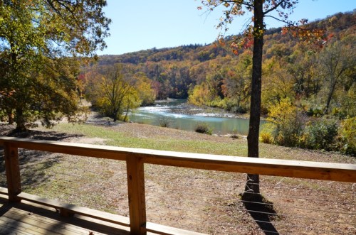 Scenic view of a river surrounded by colorful autumn trees, seen from a wooden deck.