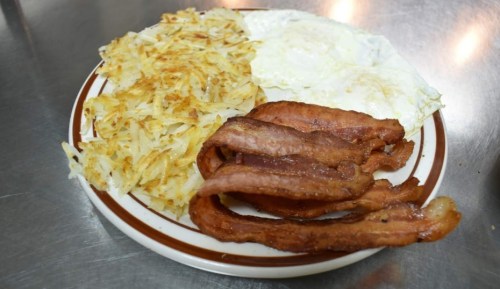 A plate of breakfast featuring crispy bacon, fried eggs, and golden hash browns.