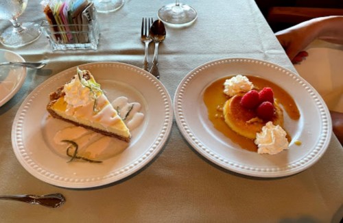 Two dessert plates: one with lemon pie and cream, the other with a flan topped with raspberries and whipped cream.
