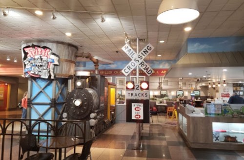 Interior of a restaurant featuring a train-themed decor, including a railroad crossing sign and a vintage train engine.