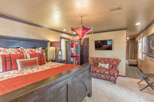 Cozy bedroom featuring a large bed, decorative pillows, a vintage-style lamp, and a plush sofa.