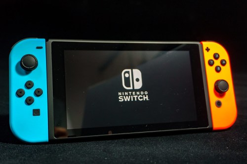 A Nintendo Switch console with blue and orange Joy-Con controllers, displaying the Nintendo logo on the screen.