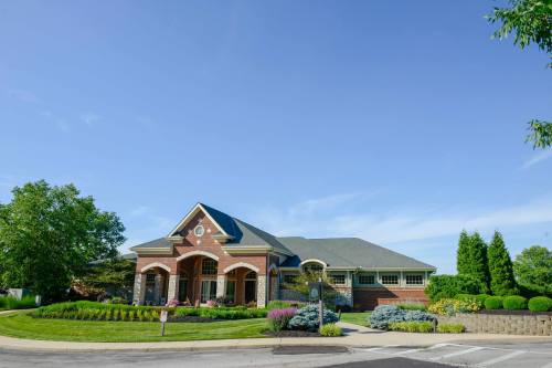 A brick building with a landscaped garden, surrounded by trees and blue sky.