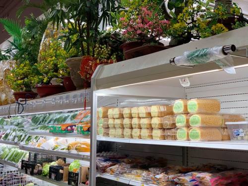 A grocery store display featuring fresh produce, packaged goods, and decorative plants on shelves.