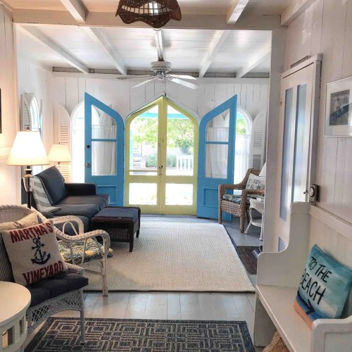 Bright, airy living space with blue doors, white walls, and cozy furniture, inviting a beachy atmosphere.