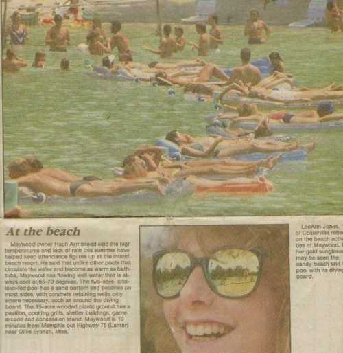 A crowded beach scene with people sunbathing and swimming, showcasing summer activities and leisure.