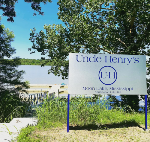 Sign for Uncle Henry's at Moon Lake, Mississippi, with a view of the lake and greenery in the background.