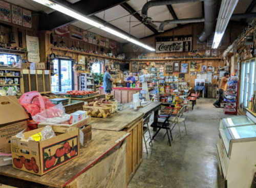 A rustic store interior filled with shelves of goods, produce, and customers browsing in a warm, inviting atmosphere.