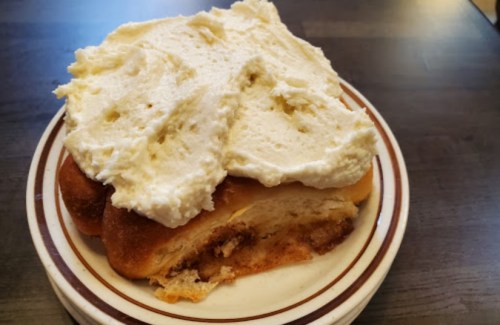 A slice of sweet bread topped with a generous layer of creamy frosting on a plate.