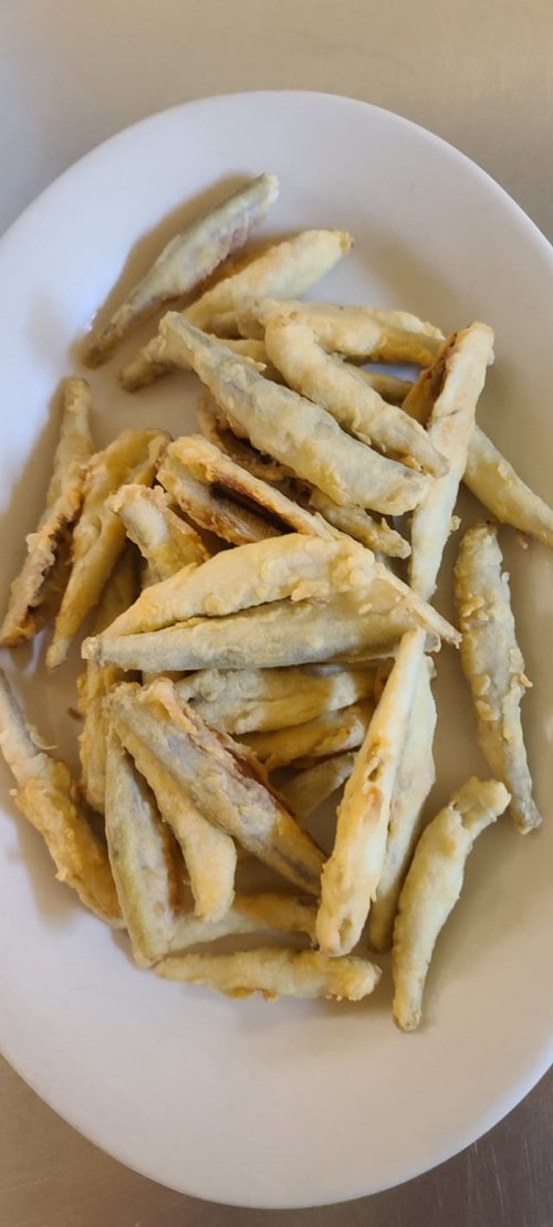 A plate of crispy fried fish, arranged in a casual pile, with a golden-brown coating.