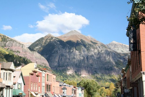 A scenic view of mountains towering over a charming town with colorful buildings under a clear blue sky.