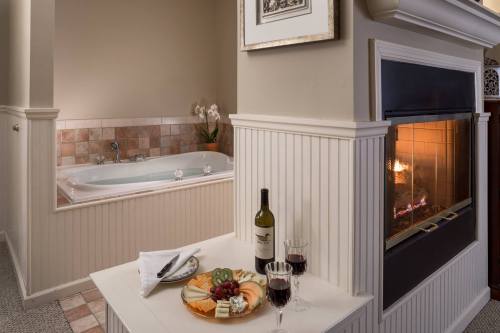 Cozy bathroom with a jacuzzi, fireplace, and a table set with wine and cheese.