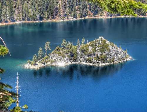 A serene lake with a small island covered in trees, surrounded by deep blue water and forested shores.