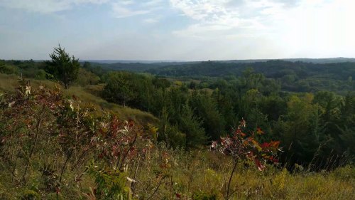 A scenic view of rolling hills and lush greenery under a partly cloudy sky.