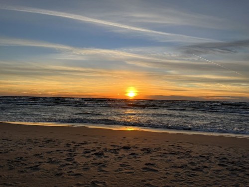A serene beach at sunset, with gentle waves and a colorful sky reflecting the fading light.
