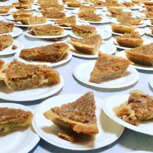 A large spread of pie slices on white plates, arranged neatly on a table.