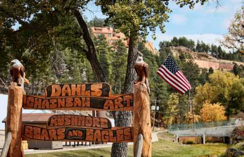 Wooden sign for "Dahl's Chasnsa Art" with "Rushmore Bears and Eagles," American flag, and trees in the background.