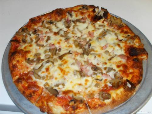 A freshly baked pizza topped with cheese, mushrooms, and ham on a metal tray.