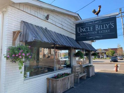 Exterior of Uncle Billy's Downtown Eatery, featuring a sign, flower boxes, and a rustic wooden bench.