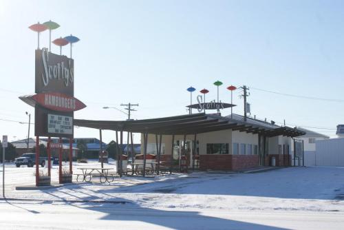 A retro-style hamburger restaurant with colorful umbrellas, surrounded by snow on a clear day.