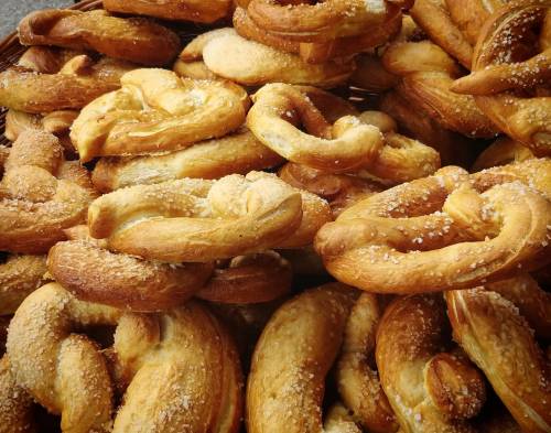 A close-up of freshly baked pretzels piled in a basket, sprinkled with coarse salt.